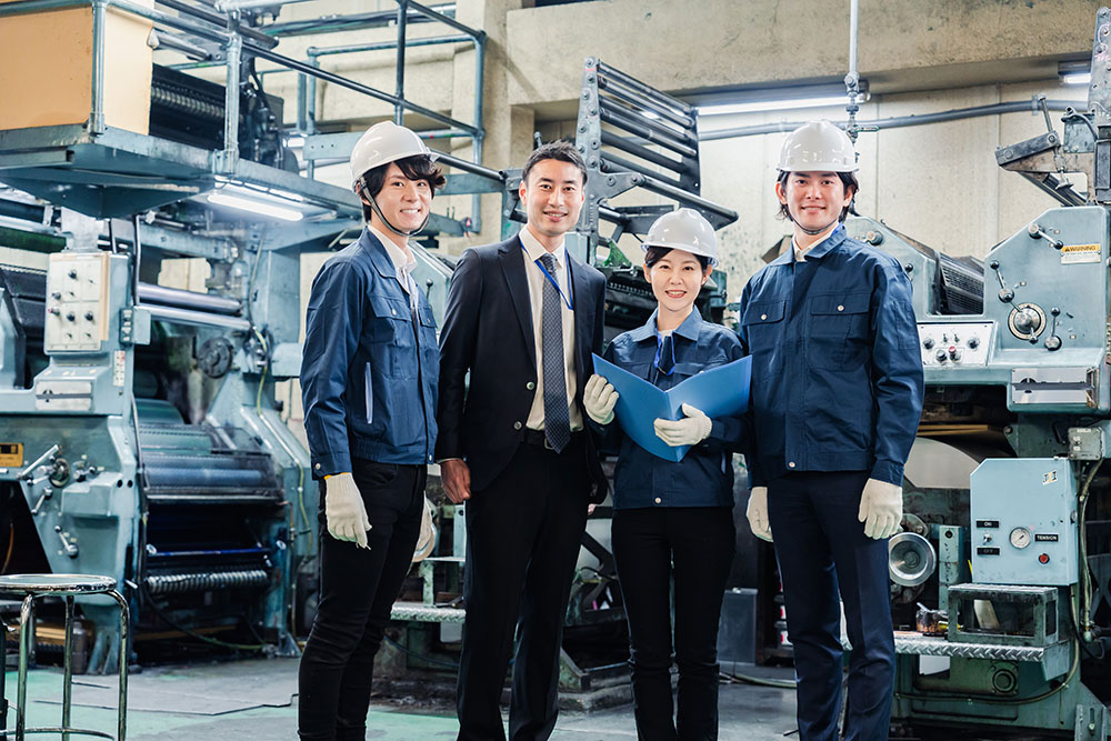 住み込み工場求人の募集先で社員4人が笑顔で並んでいるイメージ写真