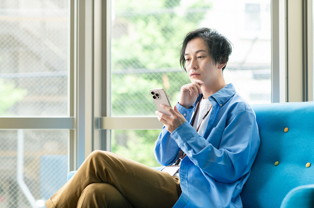 住み込み工場求人をスマホで探している男性のイメージ写真